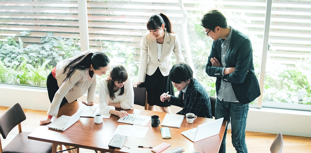 ５人のビジネスマンが相談しながらプロジェクトを進めている様子